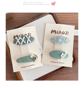 Detail of embroidered fabric hair clips with floral patterns on a display card