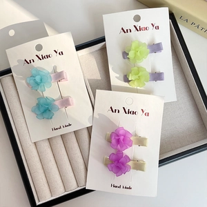 Three pairs of floral duckbill hair clips with colorful petals on white cards