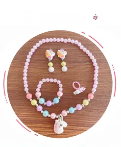 Détail de parure bijoux licorne enfant avec perles roses et breloques colorées