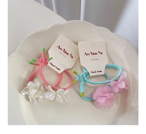 Detail of pink and blue elastic hair ties with matte resin flower charms on card