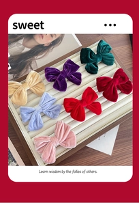 Detailed set of seven colorful velvet bow hair clips displayed on a wooden jewelry tray