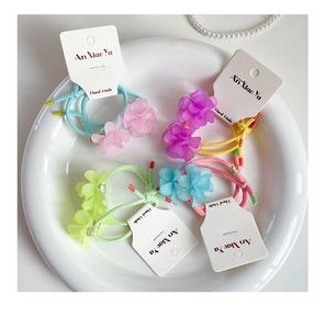 Macro shot of colorful matte flower hair ties with elastic ropes on a white ceramic plate