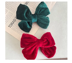 Detailed close-up of velvet bow hair clips in vibrant red and dark green fabric