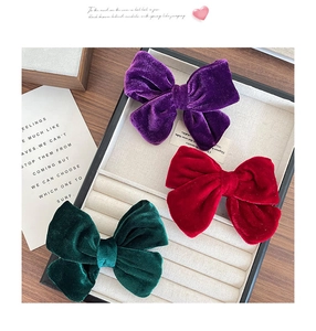 Three-piece velvet bow hair clips in purple, wine red, and dark green on display