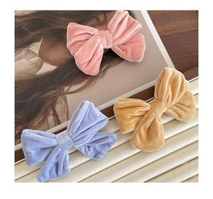 Detailed texture of velvet bow hair clips in pink, light blue and yellow colors