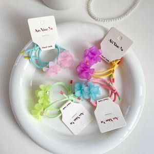 Five colorful floral resin hair ties in pastel shades on a white decorative plate
