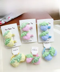 Détail de barrettes fraises faites à la main et d'élastiques aux couleurs pastel pour enfants