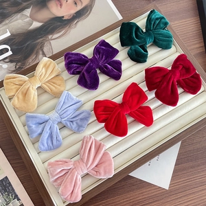 Set of 7 velvet bow hair clips in various colors displayed on a wooden stand
