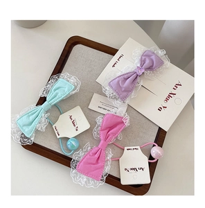 Close-up of handmade lace bow hair clips and elastics in pastel colors on display card