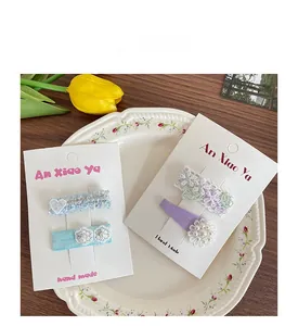 Détail de barrettes à fleurs en dentelle faites main avec perles sur assiette fleurie