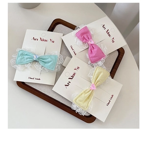 Close-up of three lace bow hair clips in mint green, pink, and yellow on display card