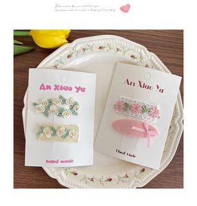 Détail de quatre barrettes à fleurs faites main avec broderie délicate sur carte blanche
