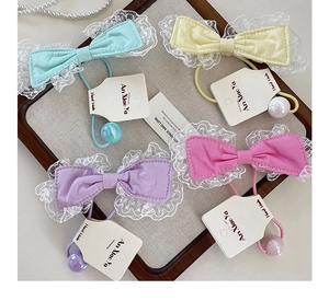 Set of four lace-edged bow hair ties with iridescent pearl charms in candy colors