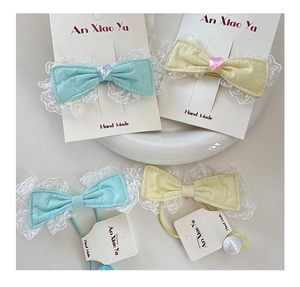 Detailed shot of bow hair clips with delicate white lace trim and heart crystal accents
