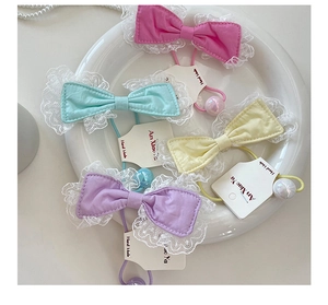 Detail of candy-colored lace bow hair ties with pearl beads in a decorative tray