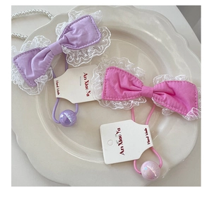Detail of sweet bow hair ties with white lace edges and iridescent beads on a ceramic plate