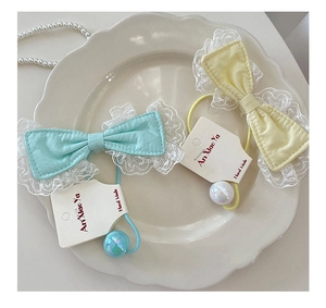 Detail of sweet lace bow hair ties with iridescent beads on a premium paper card