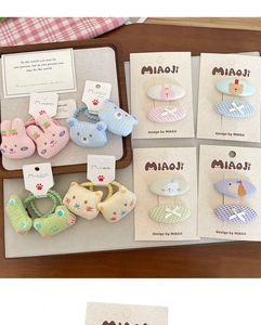 Close-up of embroidered bear and rabbit hair clips with checkered patterns in pastel colors