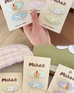 Detail of embroidered cartoon bear and plaid fabric hair clips for kids on card