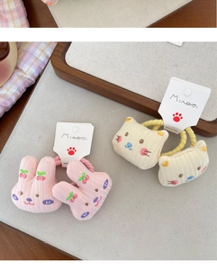 Close-up of cute plush bunny and cat hair ties with detailed cherry embroidery