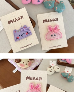Detail of handmade embroidered animal hair clips and elastics featuring cat and bear designs