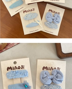 Close-up of light blue tweed and lace bow hair clips set on a decorative brand card