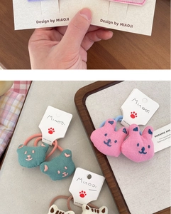 Detail of pink rabbit and green bear embroidered plush hair ties on wood display