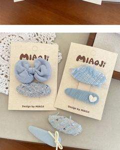 Detail view of blue tweed and chiffon bow hair clips set on a decorative card