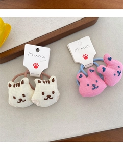 Detailed macro of handmade embroidered animal hair ties with soft plush bear and cat charms