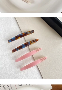 Detailed shot of four acetate willow leaf hair clips with elegant marble patterns and gold engraving