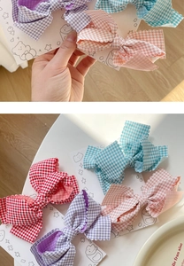Detail view of plaid bow hair clips with scalloped edges in various pastel colors