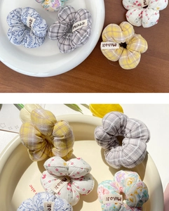 Détail de chouchous fleurs en tissu aux motifs vintage posés sur une assiette en céramique