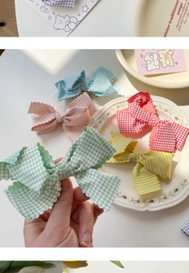 Detail of colorful plaid bow hair clips with wave edges in green, yellow and red colors