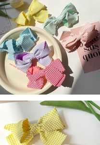 Detail of multi-color plaid bow hair clips with wave edges and delicate fabric texture