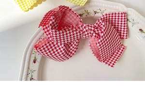 Detailed macro view of checkered bow hair clips with scalloped edges on a ceramic plate