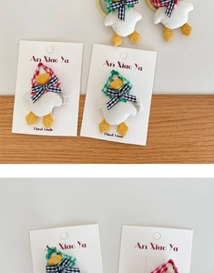 Close-up of handmade cartoon duck hair clips with red and green plaid headband details