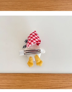 Detail view of cartoon duck hair clip with red plaid hat and metal alligator clip