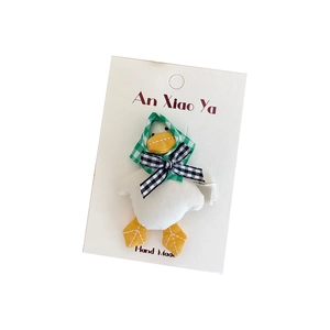 Cute plush duck hair clip with green plaid headscarf and bow on a display card