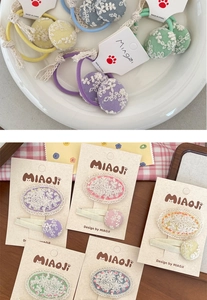 Détail des pinces à cheveux et élastiques avec broderie en dentelle aux tons pastels