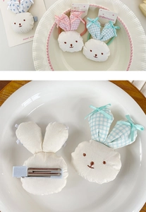 Detail of handmade plush bunny hair clips with gingham ears and embroidery on ceramic plate