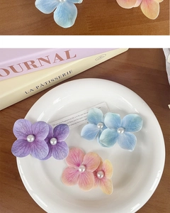 Close-up of orchid flower hair clips with gradient petals and pearls on a white plate