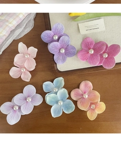 Detailed view of colorful orchid flower hair clips with central pearls on a wood surface