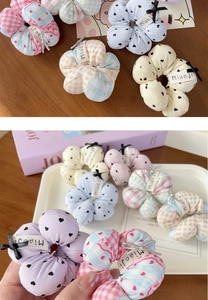 Détail d'un chouchou floral avec petit nœud et étiquette miao ji sur du bois