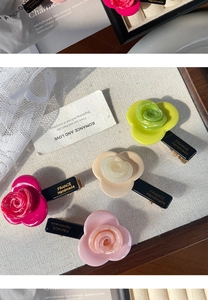 Close-up of handmade rose acetate hair clips in green, beige, magenta and pink