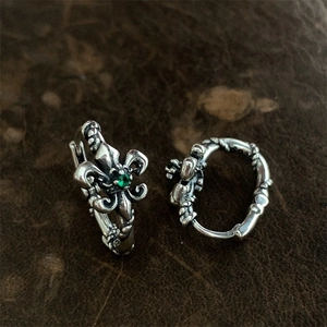 Makroaufnahme von Vintage Fleur-de-Lis Ohrringen mit grünem Zirkon auf Leder
