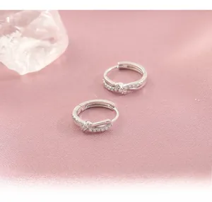 Detailed view of silver twisted hoop earrings with inlaid white zircon on silk