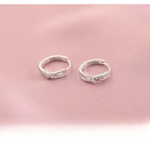 Detailed view of silver twist earrings with pavé crystals on soft pink silk background