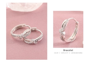 Close-up of silver twist hoop earrings with sparkling cubic zirconia on pink fabric