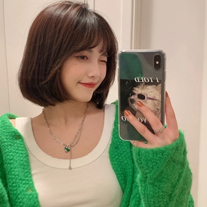 Gros plan d'un collier chaîne argentée avec pendentif cœur vert sur un mannequin
