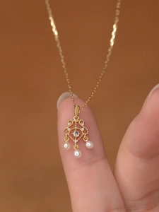 Vue macro d'un pendentif vintage en or avec petits diamants et trois perles blanches